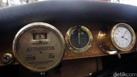 Speedometer masih manual dan menunjukkan angka mil per jam. Di sampingnya ada jam berdesain klasik.