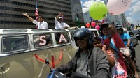 Anies dan Sandiaga menyapa warga melalui sunroof.