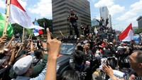 Agus yang mengenakan baju tacticool warna hitam naik ke atap mobil untuk menyapa pendukungnya.