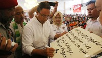 Anies memberi pesan kampanye di atas kanvas yang ia tandatangani.