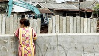 Seorang warga melihat proses pemasangan turap.