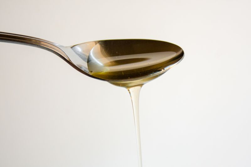 Agave nectar running off a metal spoon.