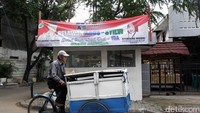 Seorang pedagang melintas di depan spanduk Agus-Sylvi.