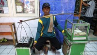 Penjual kue pancong mencari pembeli di lorong rusun.