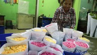 Penjual di depan deretan kuntum bunga.