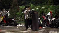 Seorang demonstran berhasil merebut tameng polisi.