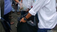 Pendemo bahu-membahu membersihkan sampah.