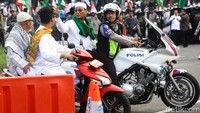 Aksi simpatik juga dilakukan oleh seorang personel polisi yang terlihat membonceng peserta demo.
