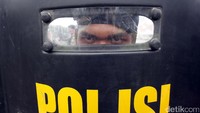Mengenakan tameng, seorang polisi siap menjaga Gedung DPR.