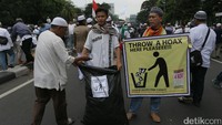 Lewat aksinya itu, para pendemo terlihat membuang sampah dalam kantong plastik.