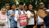 Ahmad Dhani memamerkan poster di depan kamera.