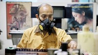 Budi Ismanto mengenakan masker untuk menampik bau dan resiko zat kimia. Cairan tersebut untuk membersihkan roll film sebelum dipindai menjadi digital.