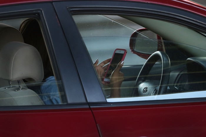 Ilustrasi menyetir mobil NEW YORK, NY - APRIL 30: A driver uses a phone while behind the wheel of a car on April 30, 2016 in New York City. As accidents involving drivers using phones or other personal devices mount across the country, New York lawmakers have proposed a new test called the Textalyzer to help curb mobile phone usage behind the wheel. Similar to a Breathalyzer test, the Textalyzer would allow police to request phones from drivers involved in accidents and then determine if the phone had been used while the drivers operated their vehicles. The controversial bill is currently in the early committee stage. According to statistics, In 2014 431,000 people were injured and 3,179 were killed in car accidents involving distracted drivers. (Photo by Spencer Platt/Getty Images)