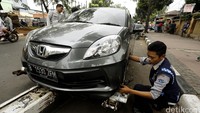 Petugas Dishub menderek mobil yang parkir sembarangan.