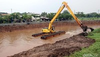Ekskavator menyusuri sungai untuk mengeruk lumpur yang mengendap di dasar sungai.