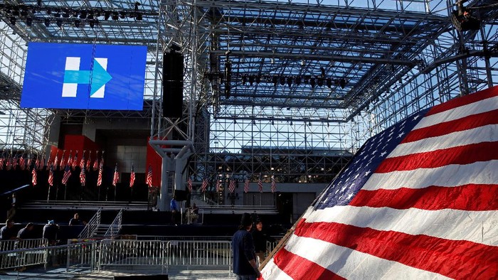 Workers stand by a U.S. flag near the stage where U.S. Democratic presidential nominee Hillary Clinton will deliver her election night speech at the Jacob K. Javits Convention Center in New York, U.S., November 7, 2016. REUTERS/Shannon Stapleton