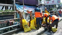 Sementara di tempat lain, petugas membersihkan sampah sisa banjir.