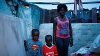 Marie Ange St Juste, bersama kedua putranya Kingsley dan Peterley berpose di dalam rumahnya yang telah hancur pasca diterjang Badai Matthew di kawasan Jeremie, Haiti, Kamis (10/11/2016) waktu setempat. Saya kehilangan segalanya, tapi saya beruntung anak-anak saya tidak ada yang meninggal, kami butuh bantuan, kata Marie. REUTERS/Carlos Garcia Rawlins.