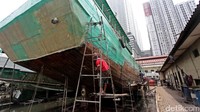 Sejumlah pekerja memperbaiki lambung kapal nelayan.