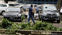Seorang warga melintas di depan mobil yang kacanya pecah.
