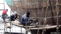 Tiga orang pekerja mengganti paku kapal.