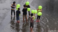 Sejumlah anak-anak bermain sambil memegang balon.