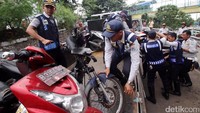 Petugas Dishub menaikkan motor yang terjaring razia ke atas truk.