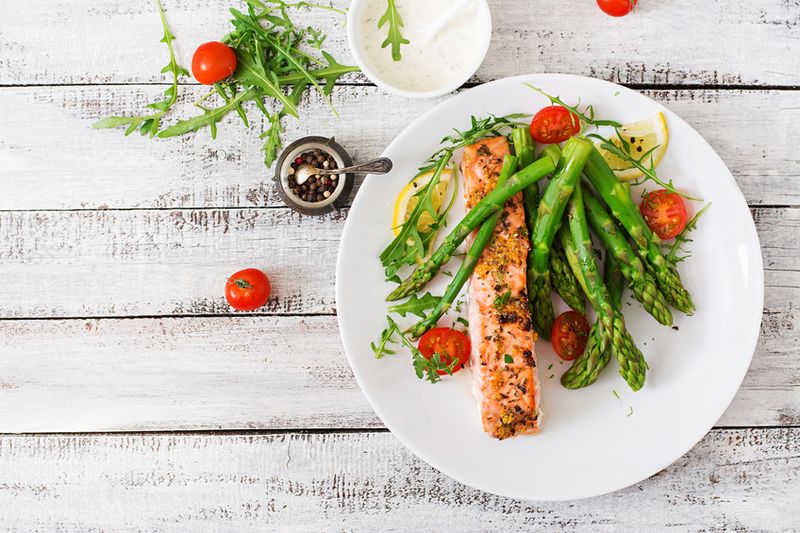 Salmon panggang Baked salmon garnished with asparagus and tomatoes with herbs. Top view