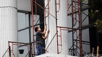 Seorang pekerja nampak memegangi tali tanpa sarung tangan dan tanpa helm proyek.