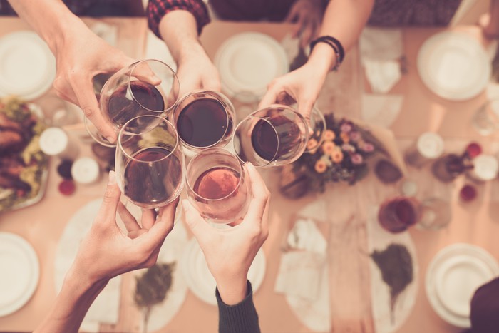Ilustrasi makan bersama Friend clinking glasses above dinner table
