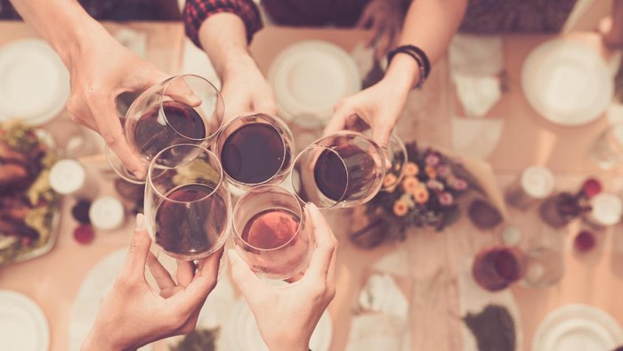 Friend clinking glasses above dinner table