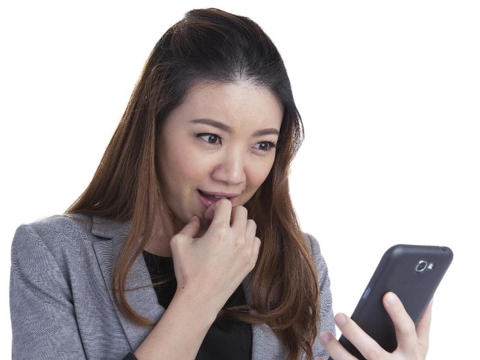 wanita kencan online Cute young woman holding a smartphone and smiling while reading from it. isolated on white background