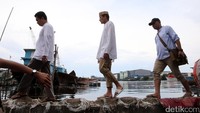 Sandiaga melepas sepatu dan mengganti sandal untuk melintasi tanggul Muara Baru yang memisahkan permukiman warga dengan laut Jakarta.