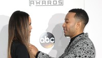 Saat diminta berpose sendiri, John Legend tampak membenarkan letak kalung yang menggantung di leher sang istri. Frederick M. Brown/Getty Images/detikFoto.