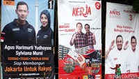 Tiga orang warga melintas di depan baliho kampanye cagub dan cawagub DKI.