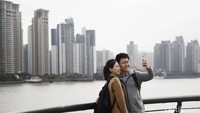 Wisatawan tengah asyik selfie dengan latar belakang The Bund.