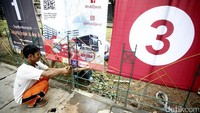 Beberapa pekerja memasang spanduk tiga pasang cagub-cawagub DKI.