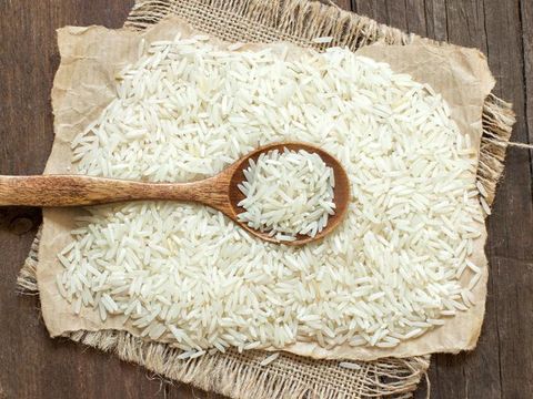 Raw rice and flour in bowls with scoop on wooden background