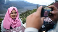Seorang risers berfoto dengan latar belakang Gunung Bromo.