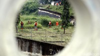 Pasukan Oranye membersihkan rumput di bantaran sungai.