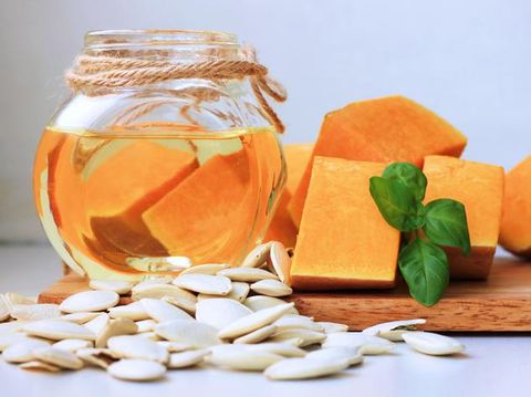 biji labu Pumpkin raw pieces, roasted seeds, basil herb, pumpkin seed oil in glass jar. Healthy culinary and cosmetic use, vegetable benefits.