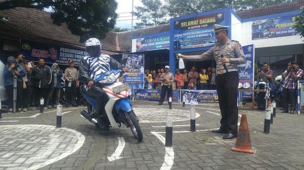 Petugas memperagakan melewati rintangan ujian SIM sembari ditembaki dengan air di titik-titik rintangan.