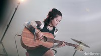 Di tengah derasnya hujan di luar,  petikan guitar dan suara merdunya membuat suasana terasa hangat.