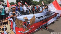 Massa membentangkan spanduk dan mengibarkan bendera merah putih.