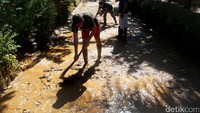 Warga membersihkan lumpur sisa banjir yang menutup jalan.