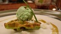 Waffle rasa pandan dengan es krim berwarna hijau mirip kue putu berisi gula merah.