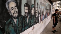 Seorang pria berdiri disamping mural Fidel Castro di Caracas, Venezuela (26/11/2016). REUTERS/Marco Bello.