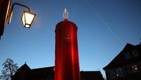 Lilin setinggi 42 meter ini bukanlah lilin sungguhan, melainkan hanya sebauh menara yang dibungkus dengan kain merah dengan ornamen lampu di puncaknya untuk memberikan kesan lilin Natal. Hannelore Foerster/Getty Images.