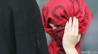 Seorang warga Maroko menutup wajahnya dengan kain berwarna merah.