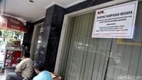 Sebuah pamflet ukuran besar bertuliskan BARANG RAMPASAN NEGARA juga ditempelkan di kaca ruko.